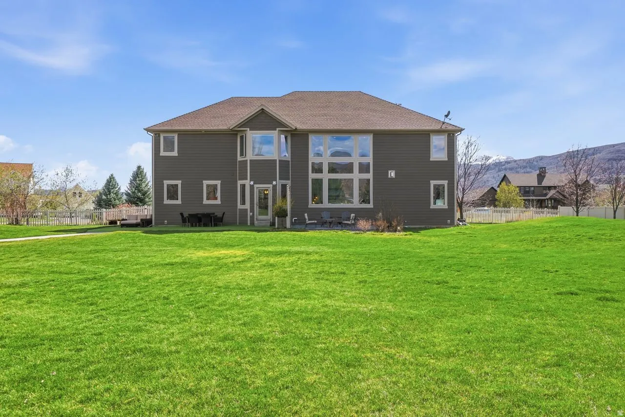 Expansive green space with a large rear facade featuring multiple windows and a private outdoor patio