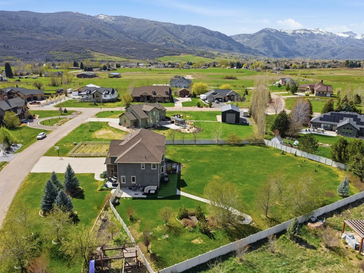 Expansive property featuring a large manicured lawn, white fencing, and mountain scenery