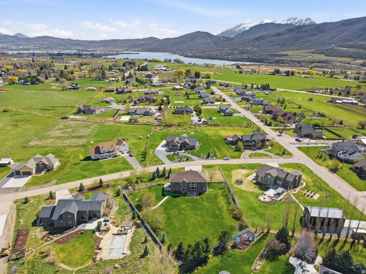 Expansive residential area featuring established homes, verdant landscapes, and a visible body of water with mountainous backdrop