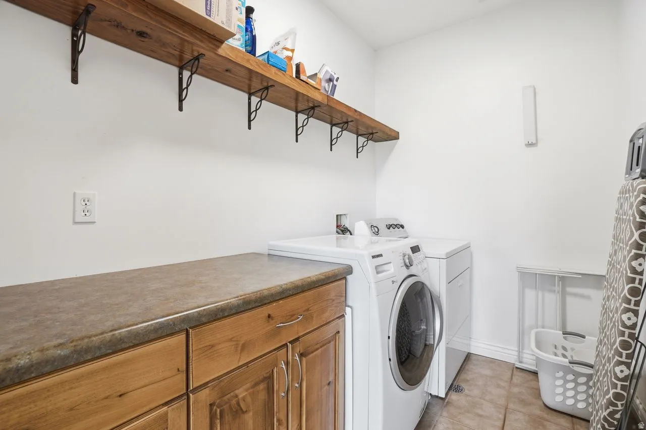 Laundry space featuring wood-finish cabinetry, a durable countertop, and open shelving with decorative brackets