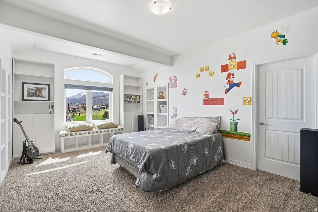Arched picture window with window seat, built-in shelving, plush carpet flooring, and a paneled interior door