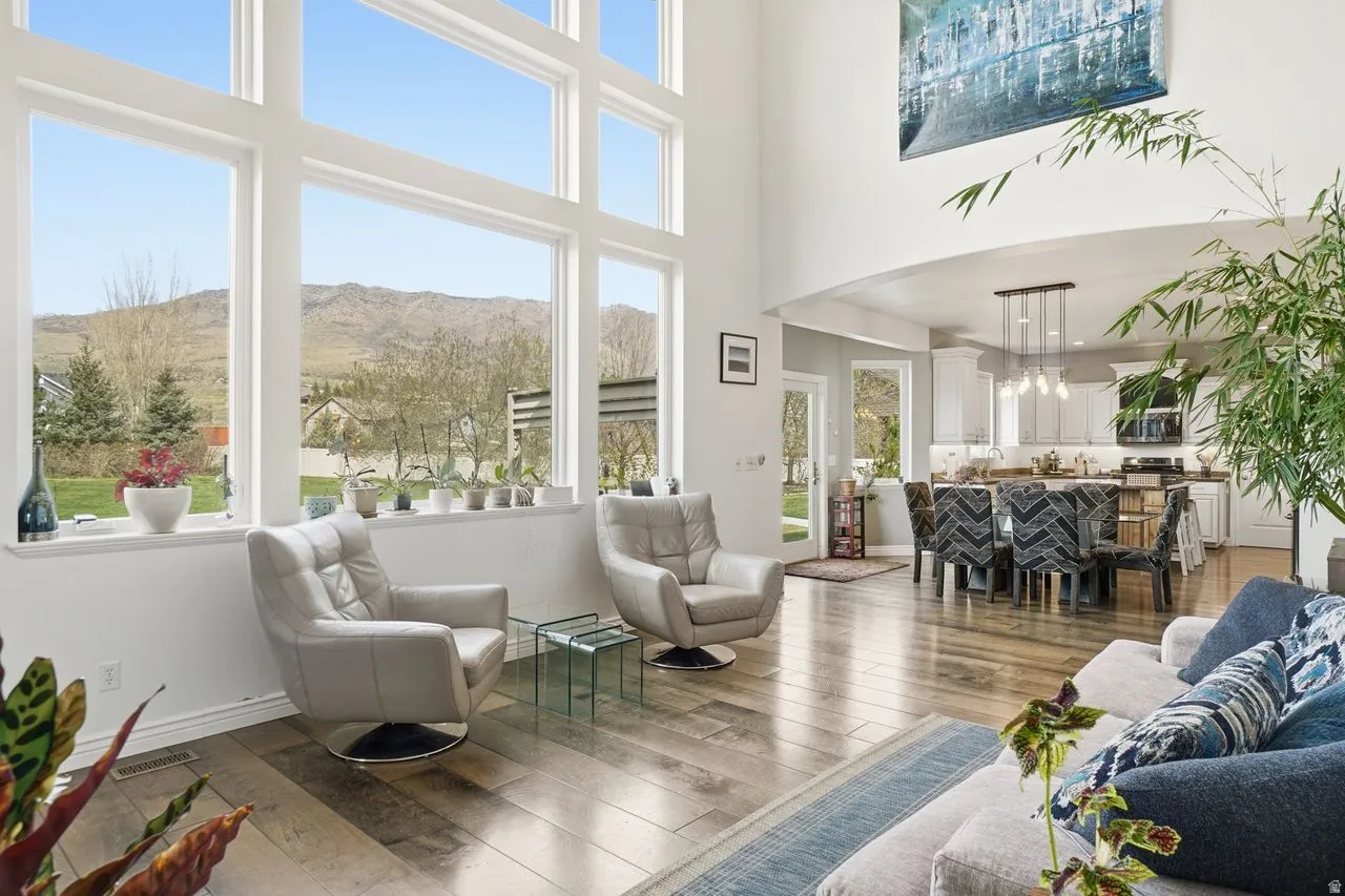 Two-story great room with expansive windows, wood-finish flooring, and a recessed ceiling archway
