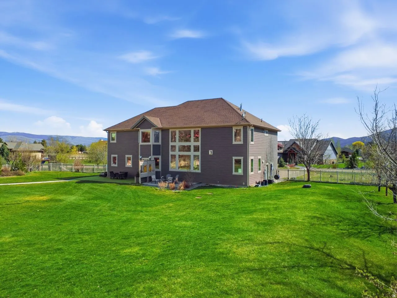 Expansive green lawn surrounds a multi-story residence with a brown shingle roof