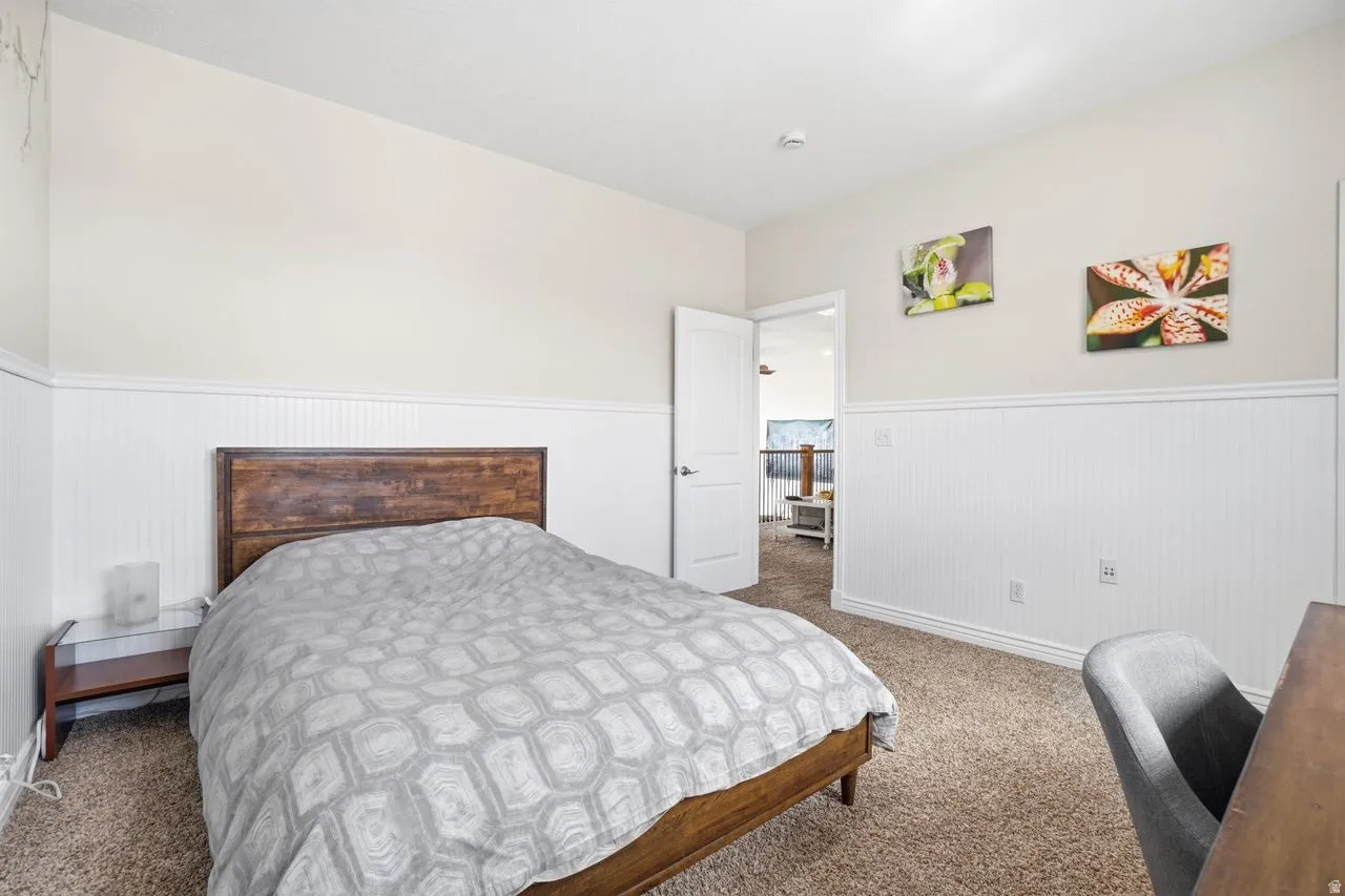 Carpeted flooring, white wainscoting, and a wood-finish headboard