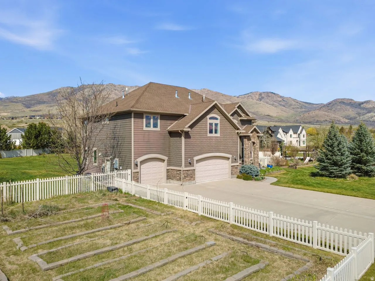 Multi-level residence featuring a two-car garage, stone and siding exterior, and a gabled roofline