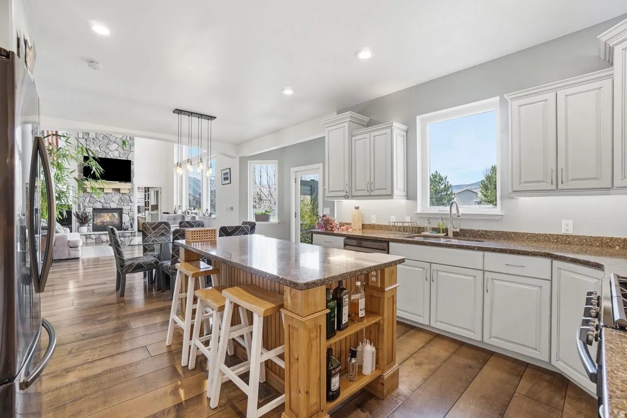 Kitchen featuring a large wood-finish island with seating, white cabinetry, integrated stainless steel appliances, and wood-finish flooring