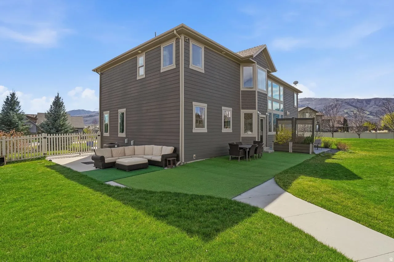 Expansive lawn area with a concrete patio, artificial turf section, and a paved walkway