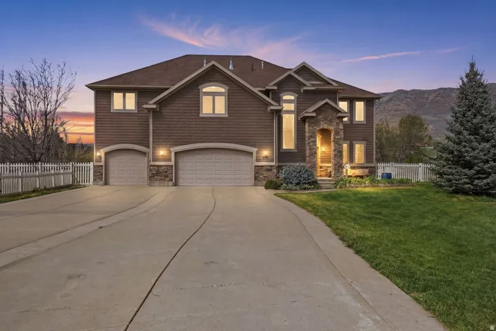 Two-story residence featuring a partial stone facade, a double garage, and an arched entry with recessed lighting