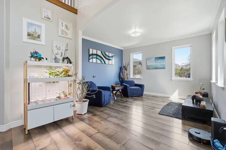 Spacious room featuring wood-finish flooring, light gray walls, and multiple windows allowing natural illumination