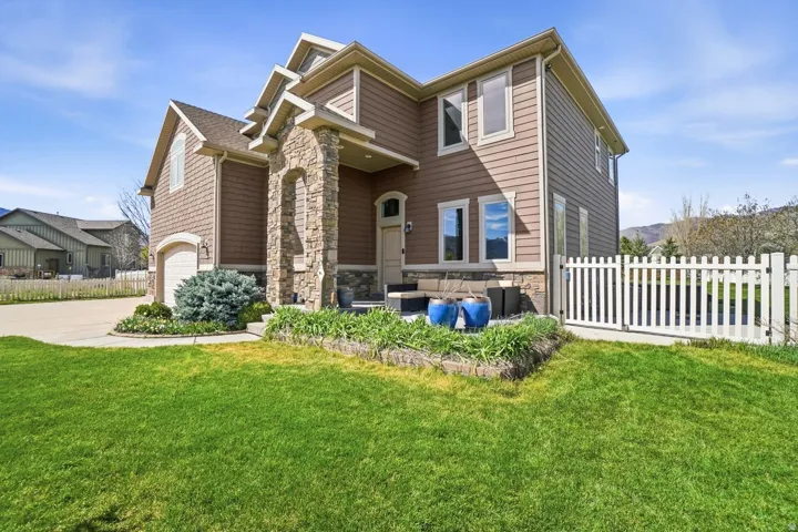 Two-story residence featuring composite siding, stone facade accents, an arched entryway, and an attached two-car garage