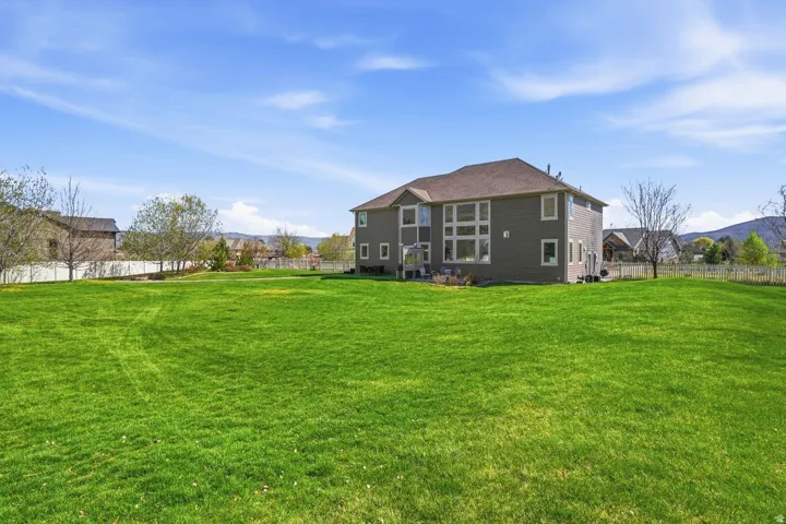 Expansive green lawn with mature trees and a fenced perimeter