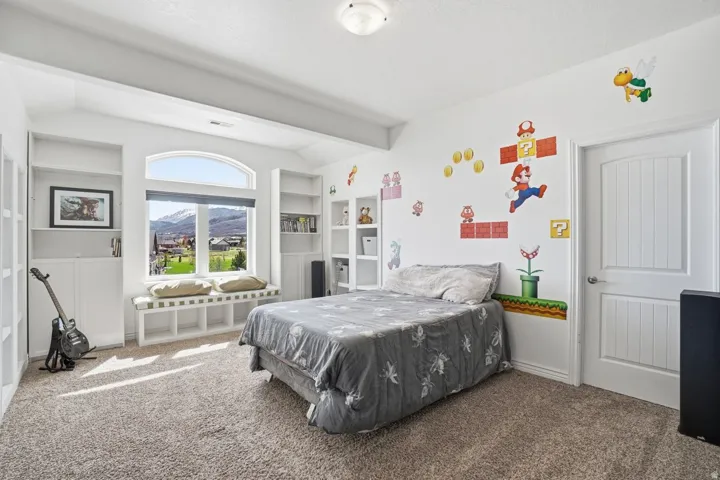 Arched picture window with window seat, built-in shelving, plush carpet flooring, and a paneled interior door