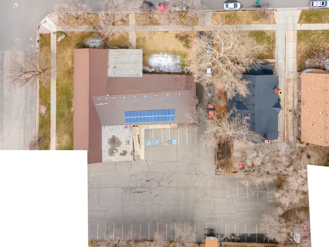 Large paved parking area, commercial building with brown roofing, solar panel installation, and designated accessible parking spaces