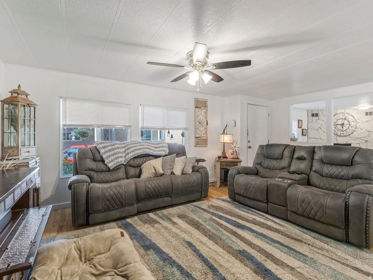 Recessed lighting in ceiling, ceiling fan with light fixture, multiple windows with blinds, wood-finish flooring