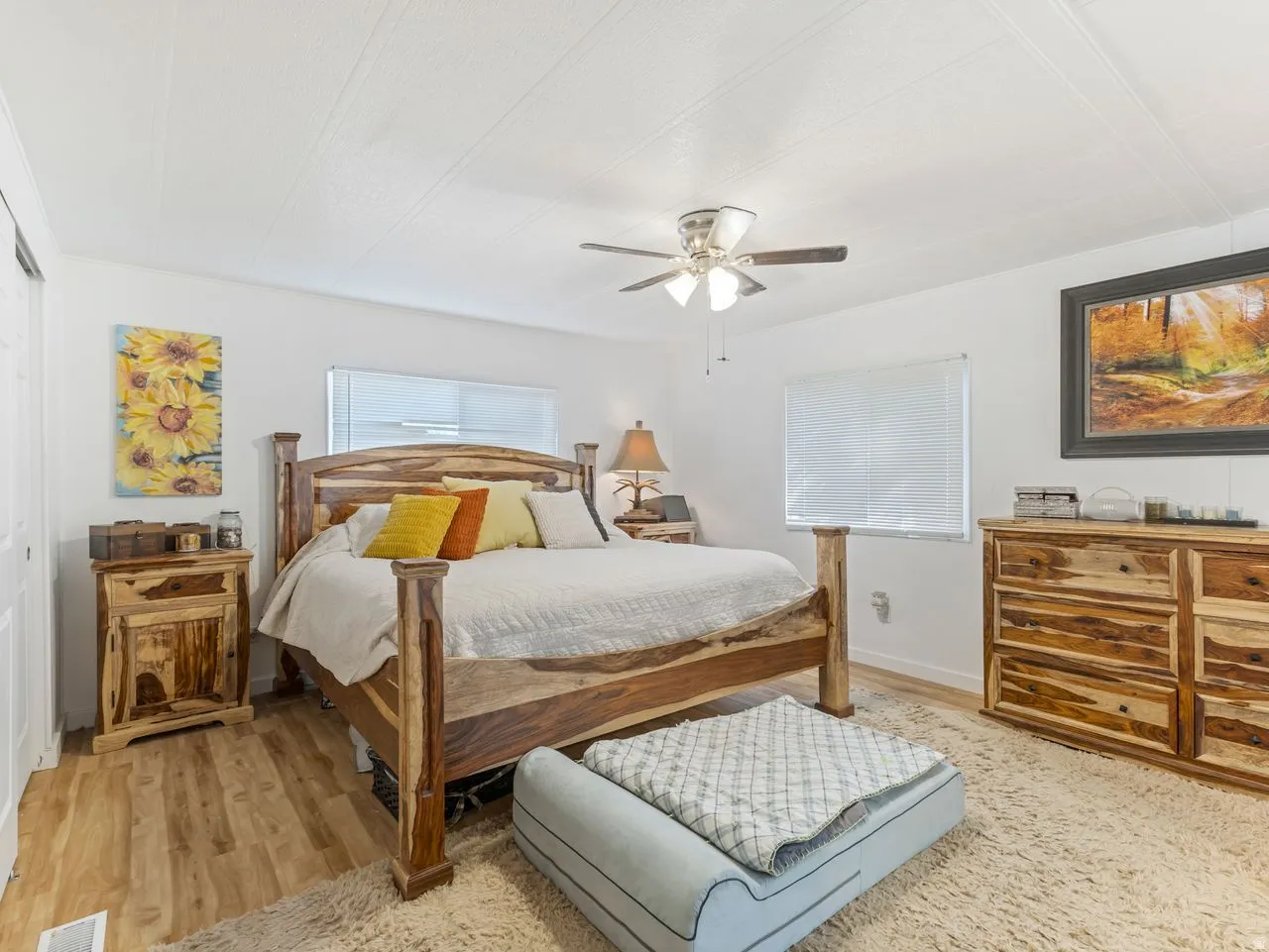 Wood-finish flooring with a light-toned area rug, neutral wall finishes, and a ceiling fan with integrated lighting