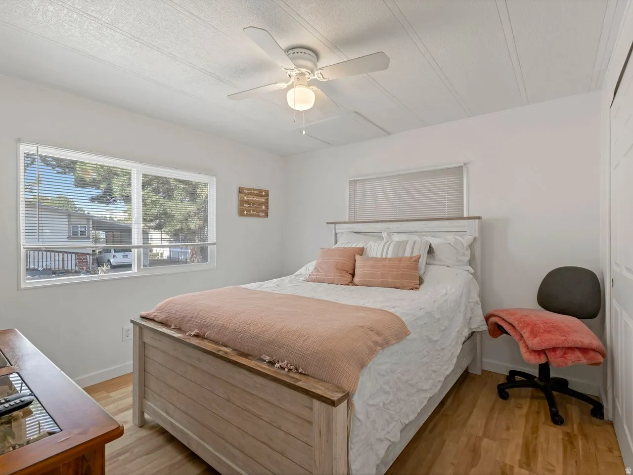 Wood-finish flooring with white walls and a white ceiling fan