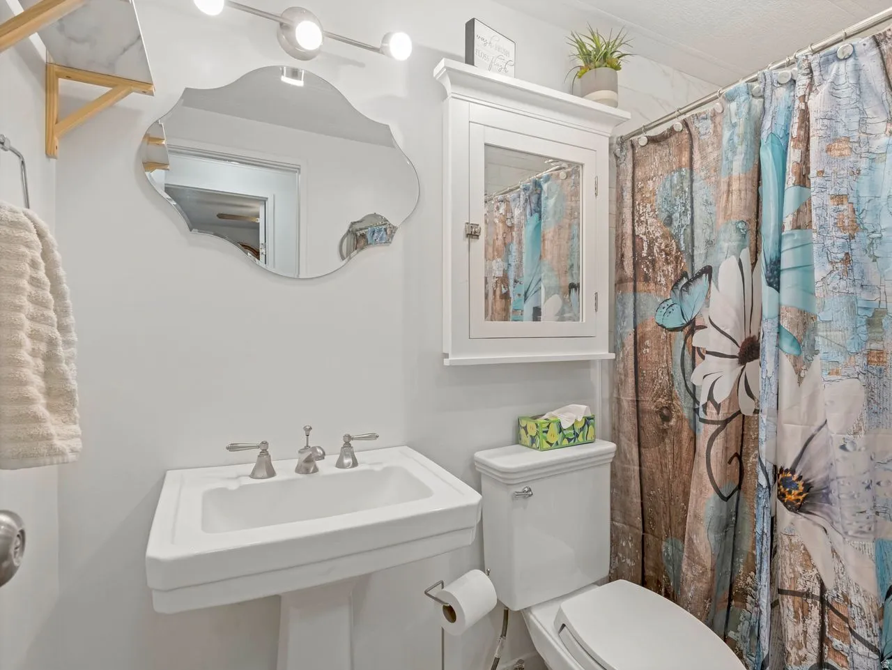 Pedestal sink with brushed nickel hardware, wall-mounted medicine cabinet, and overhead vanity lighting