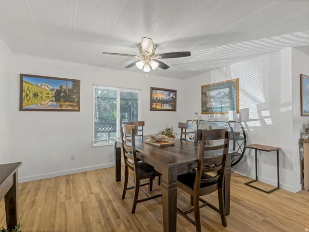 Wood-finish flooring, white walls, ceiling fan with integrated lighting, and a sliding glass window