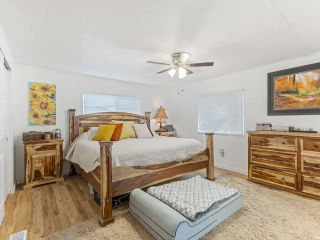 Wood-finish flooring with a light-toned area rug, neutral wall finishes, and a ceiling fan with integrated lighting