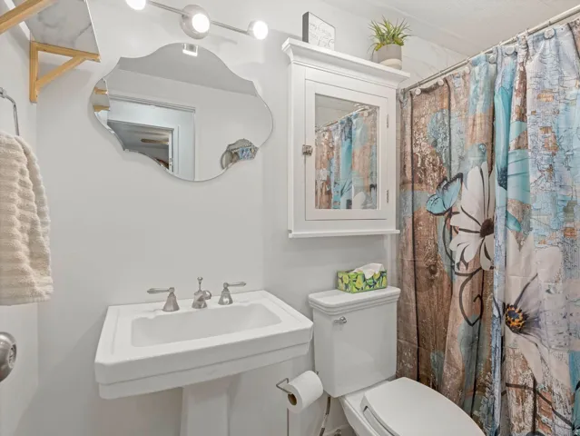 Pedestal sink with brushed nickel hardware, wall-mounted medicine cabinet, and overhead vanity lighting