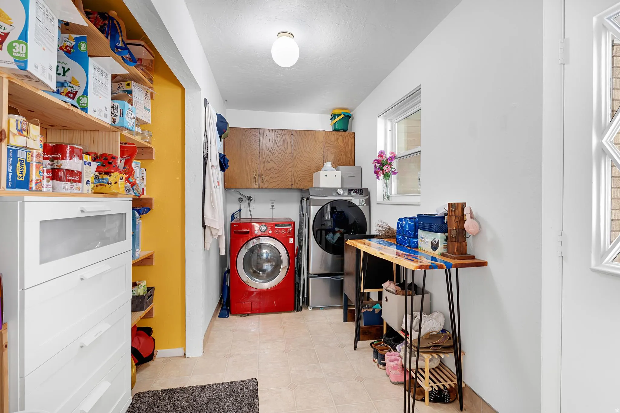 Laundry area with upper cabinetry and a window