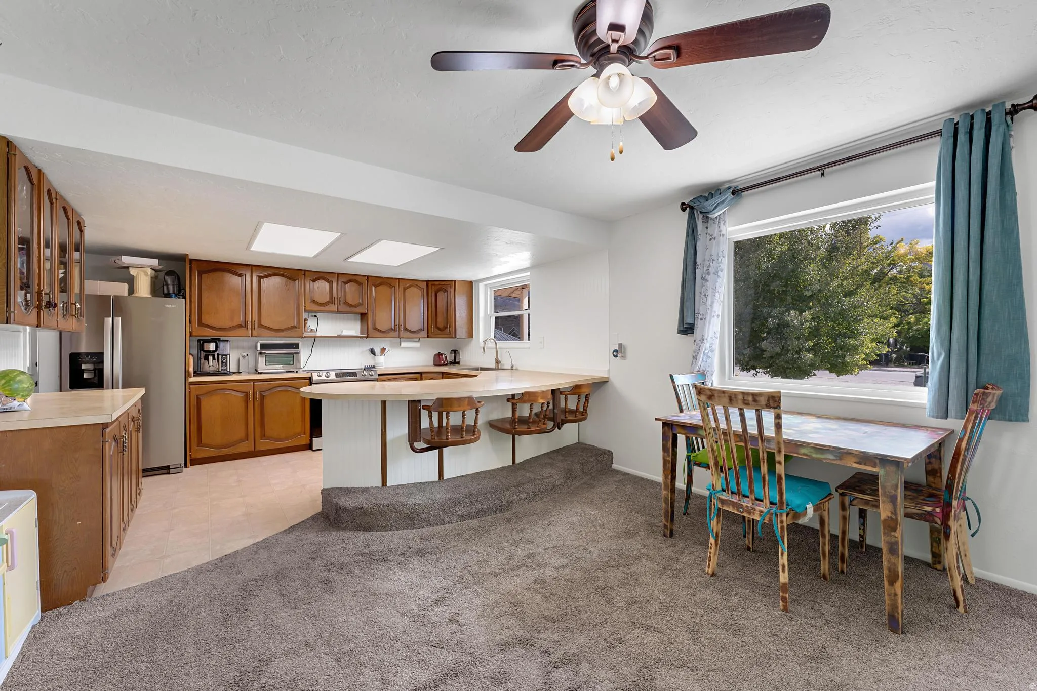 Kitchen with wood-finish cabinetry, built-in breakfast bar, and two skylights