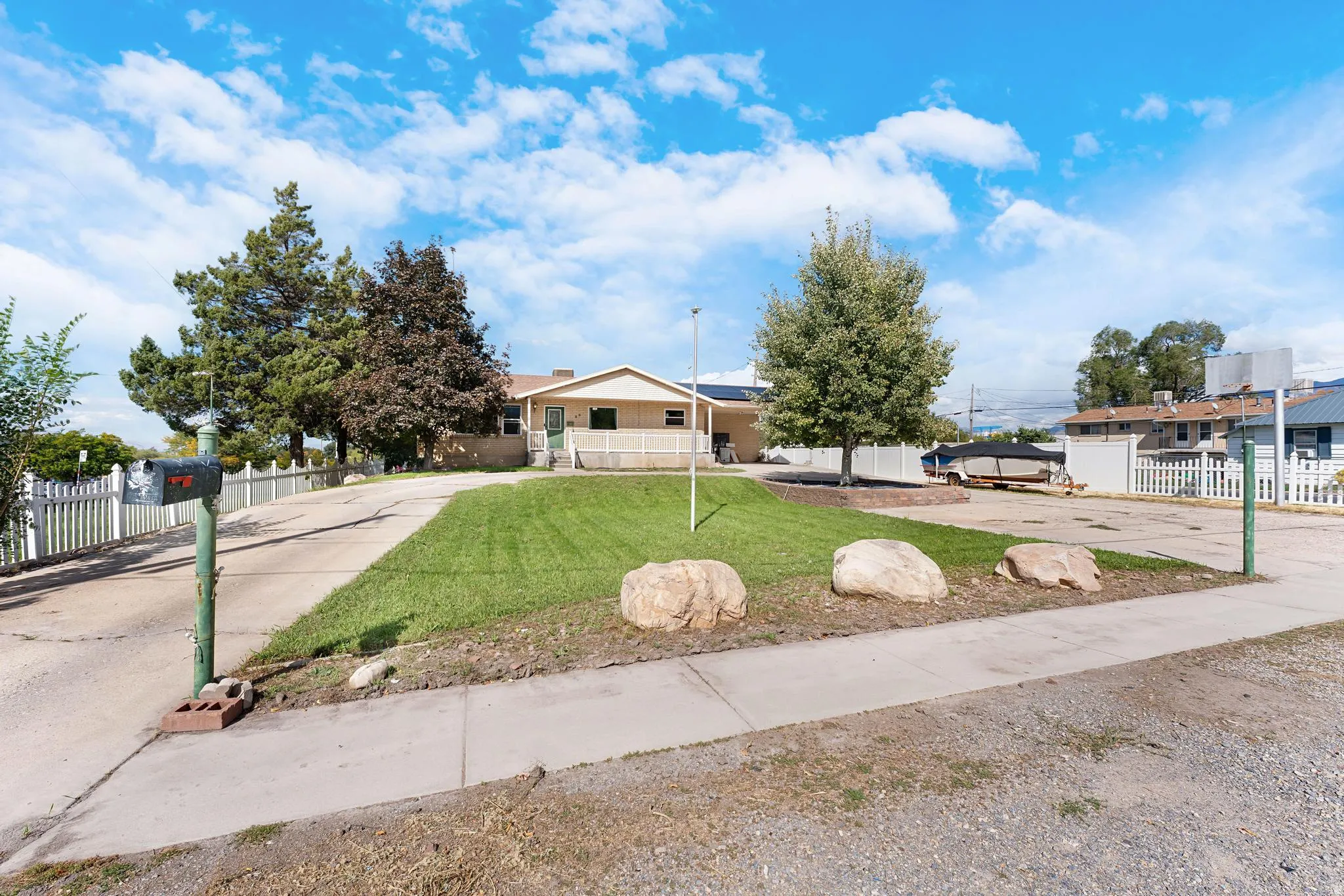 Expansive front yard with a well-maintained lawn, mature trees, and a concrete driveway