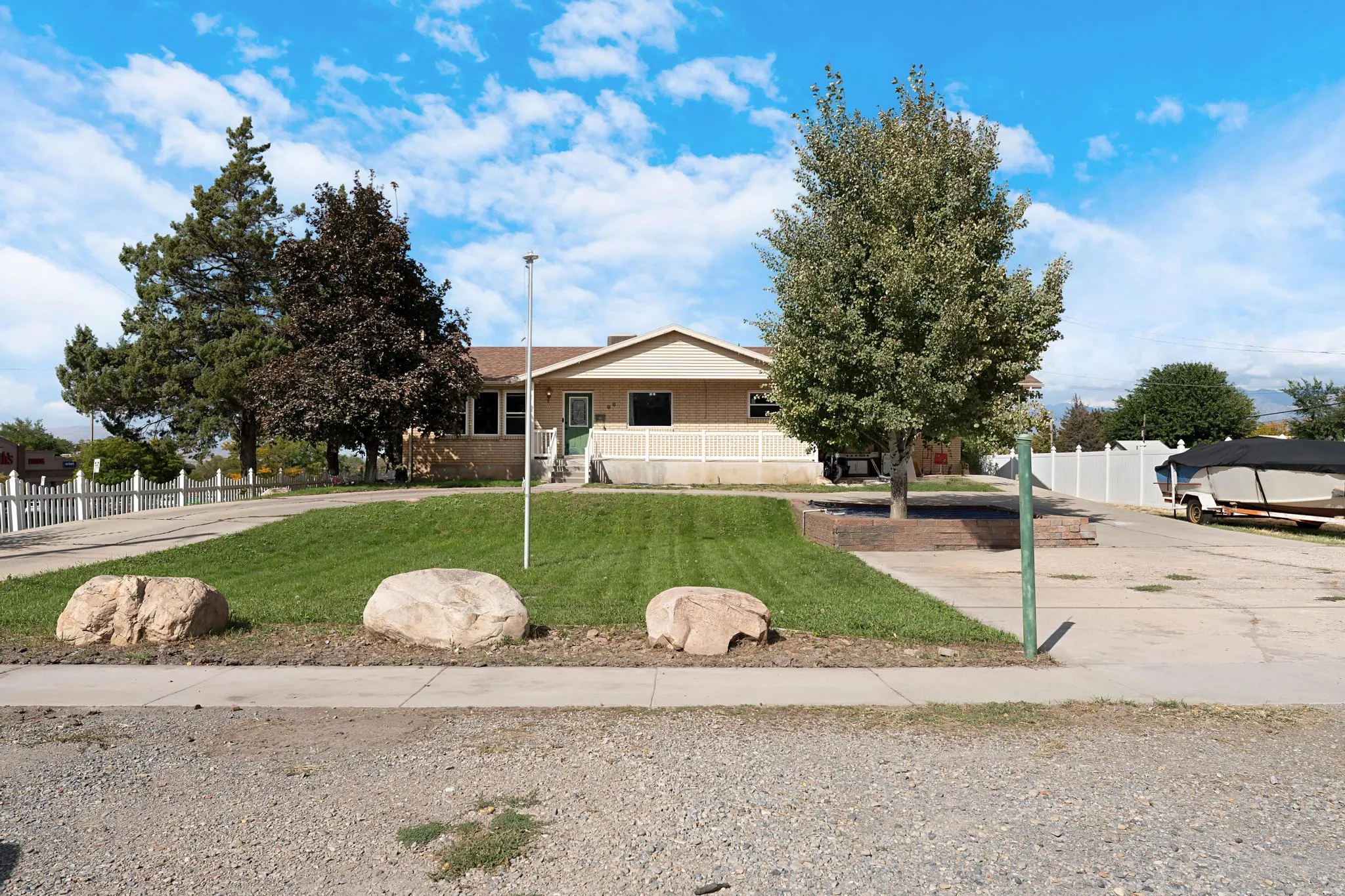 Ranch-style residence with a raised front porch, mature trees, and a spacious paved driveway