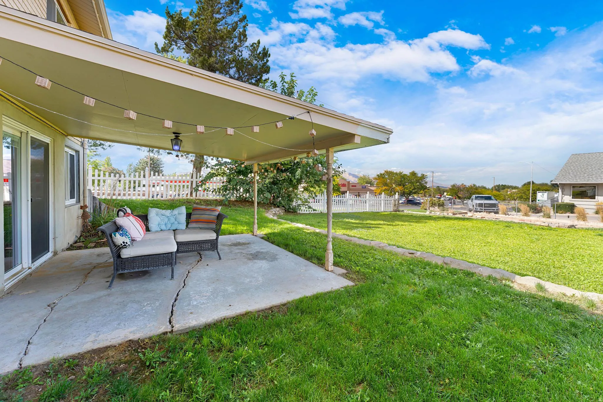 Covered patio with concrete flooring, supported by metal posts