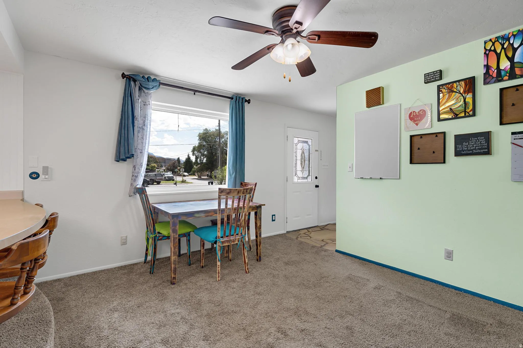 Ceiling fan with integrated lighting, expansive window, front entry door with decorative glass, carpet flooring, light-toned wall finishes