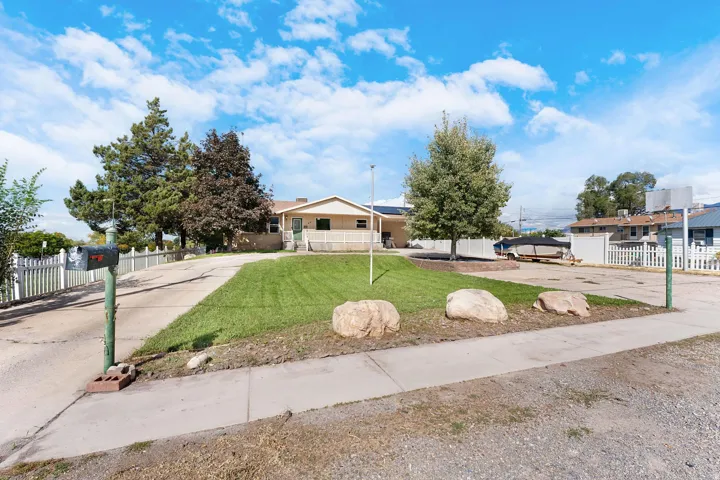 Expansive front yard with a well-maintained lawn, mature trees, and a concrete driveway