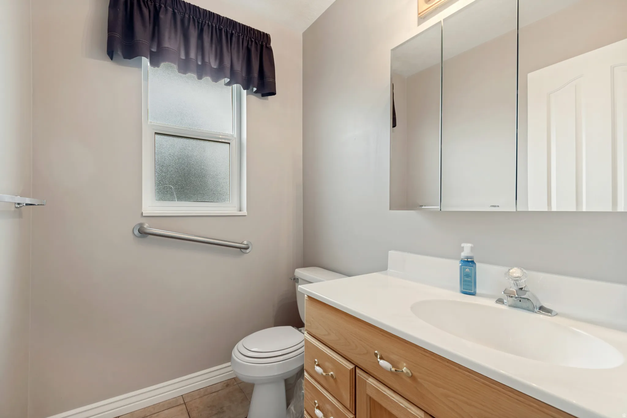 Wood-finish vanity with an integrated basin sink, mirrored medicine cabinet, and a privacy window
