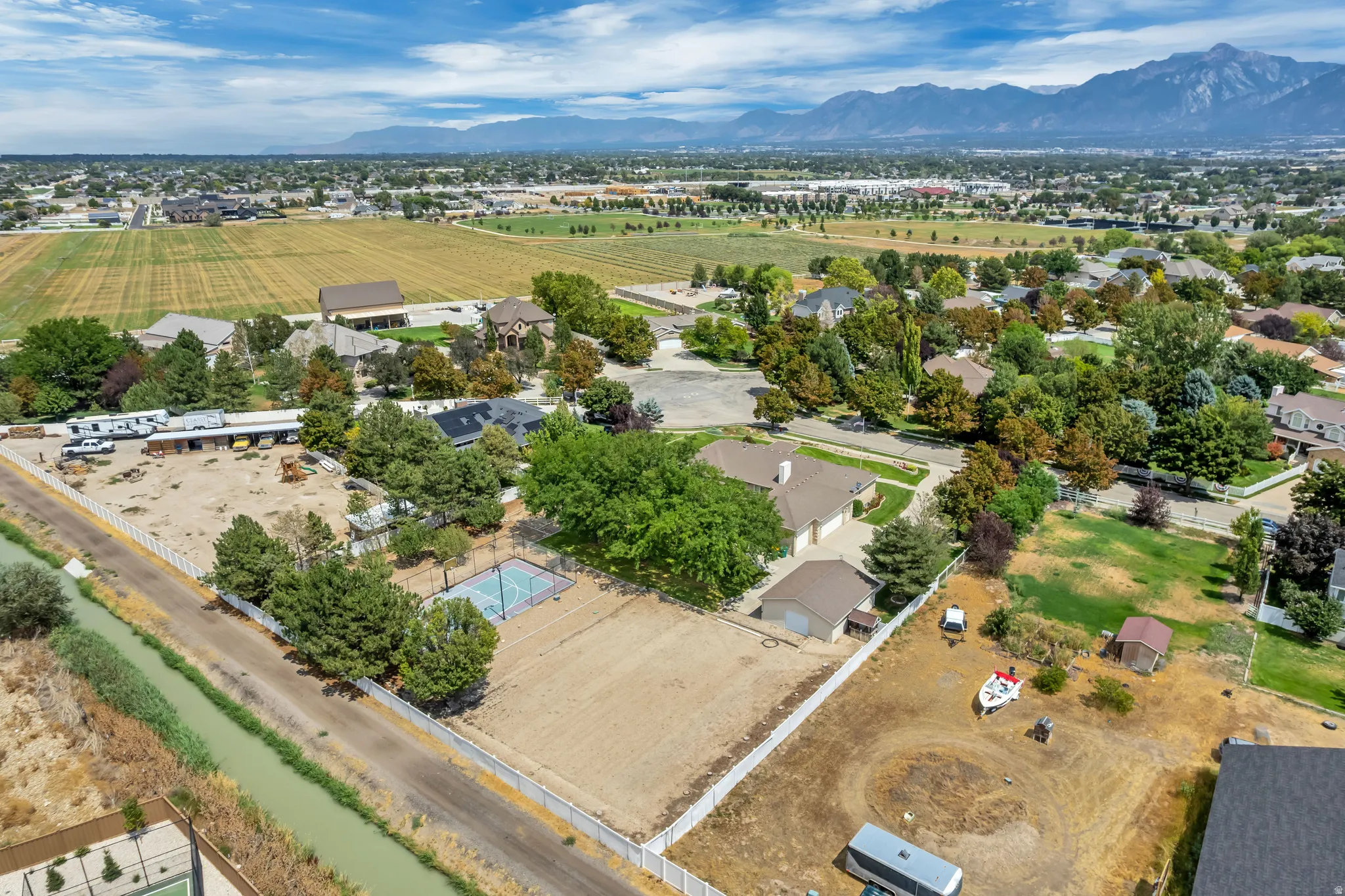 Expansive property featuring a paved sports court, multiple accessory structures, and a sizable undeveloped area