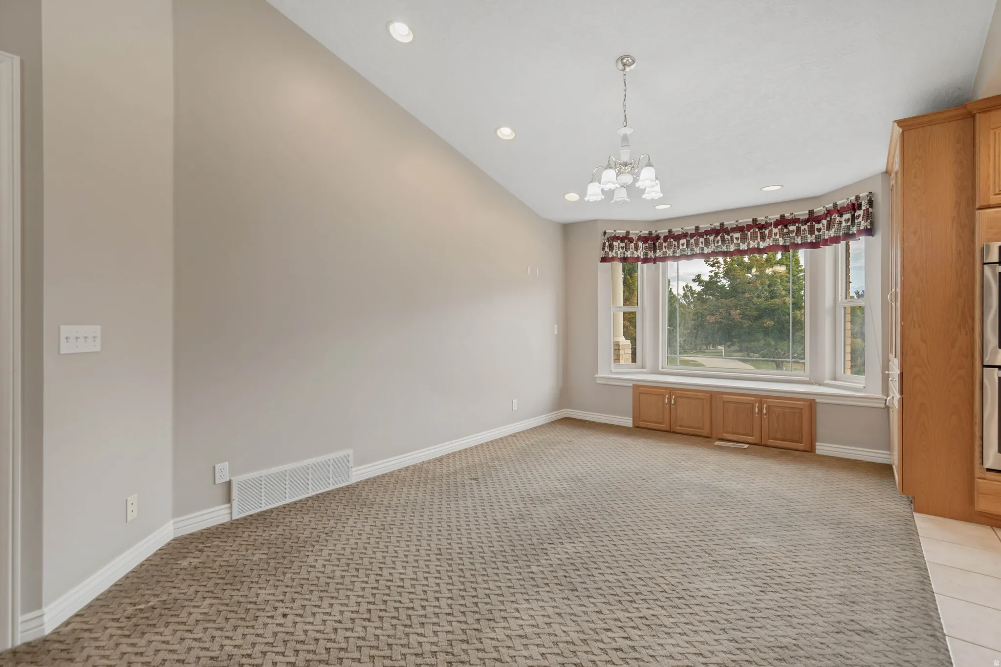 Bay window with integrated wood-finish cabinetry, recessed lighting, and a multi-light chandelier