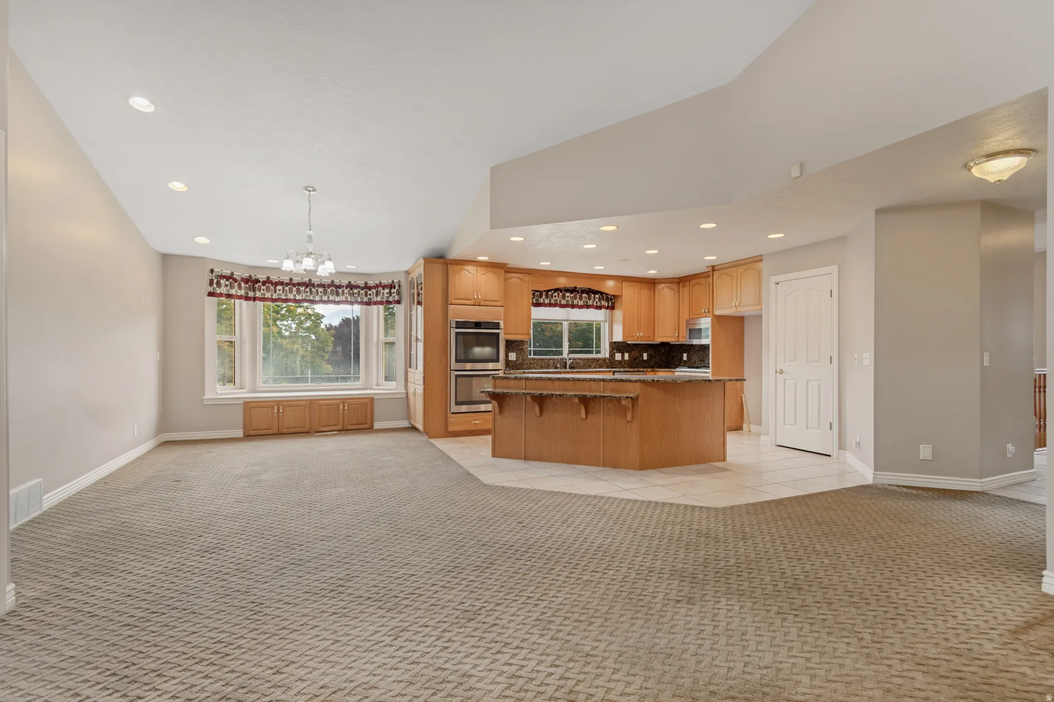 Open-concept living space with a kitchen featuring wood cabinetry, dark countertops, and stainless steel appliances