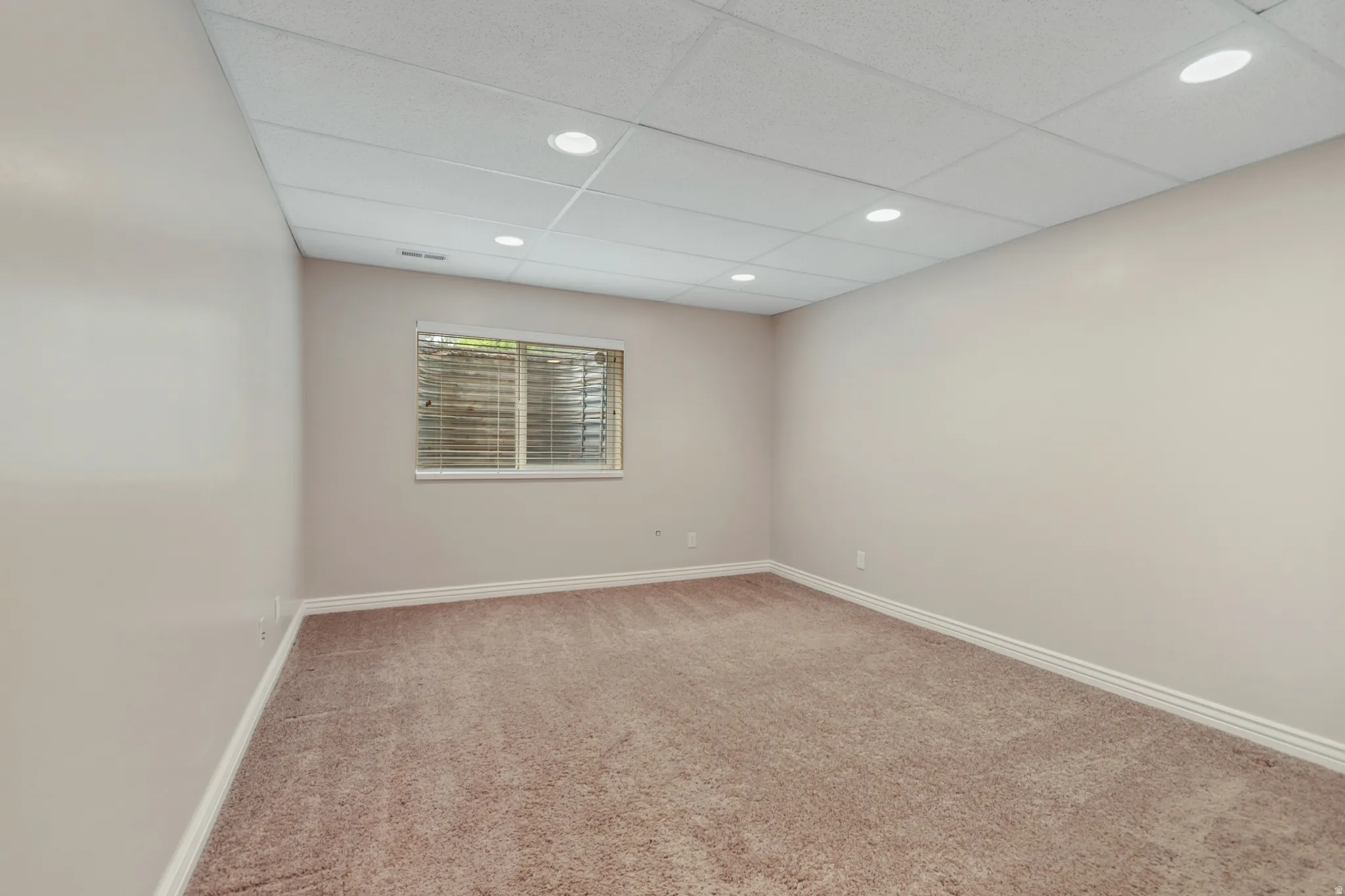 Recessed lighting, drop ceiling, window with blinds, light-toned walls, and carpet flooring