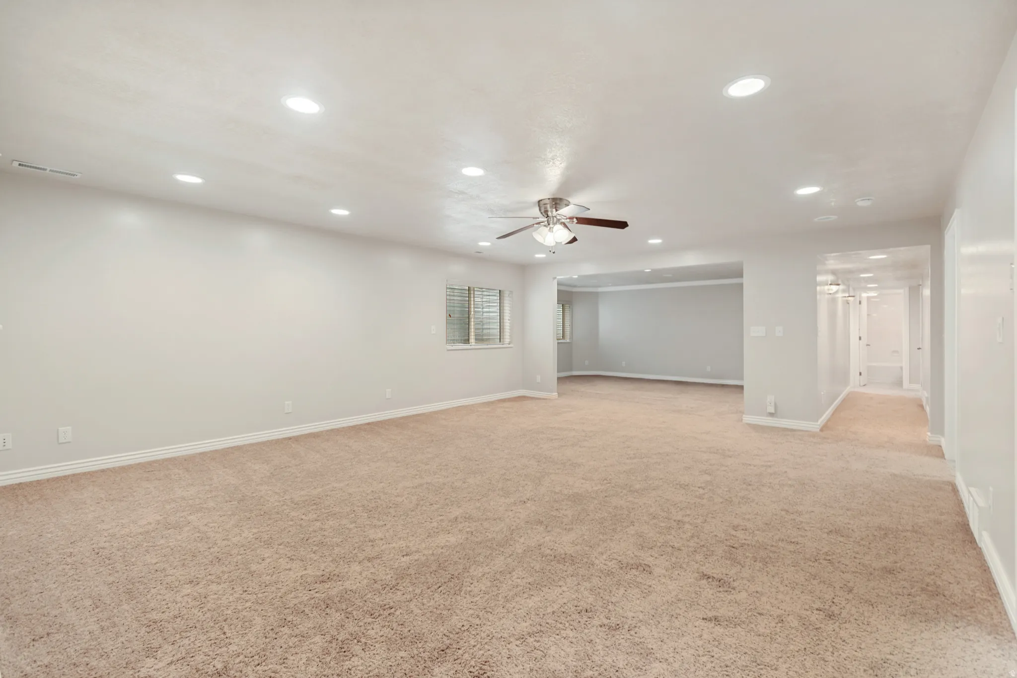 Recessed lighting, ceiling fan with light kit, neutral carpet, window with blinds, and light-toned wall paint