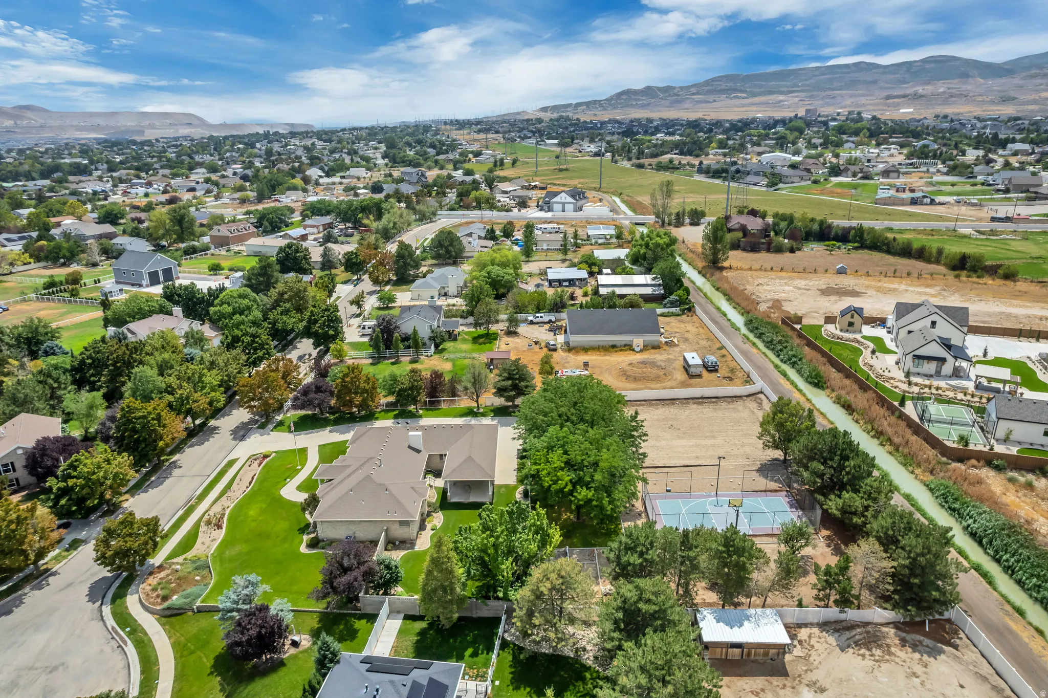 Expansive residential landscape with diverse architectural styles, visible mountain range, and a paved street with manicured lawns
