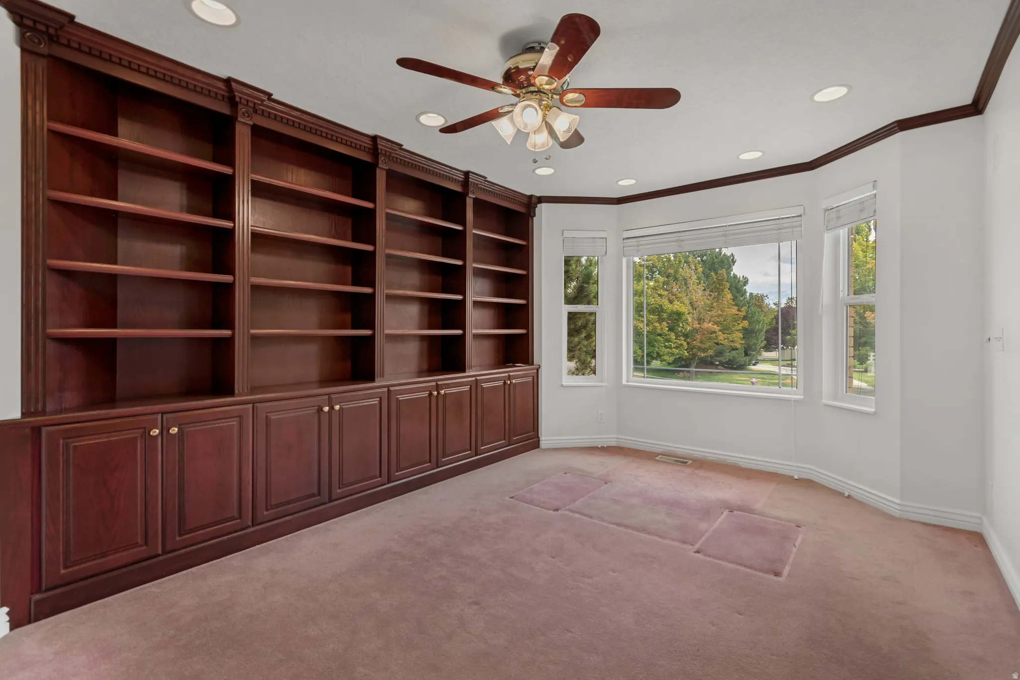 Extensive built-in wood cabinetry and shelving, recessed lighting, ceiling fan, and bay window