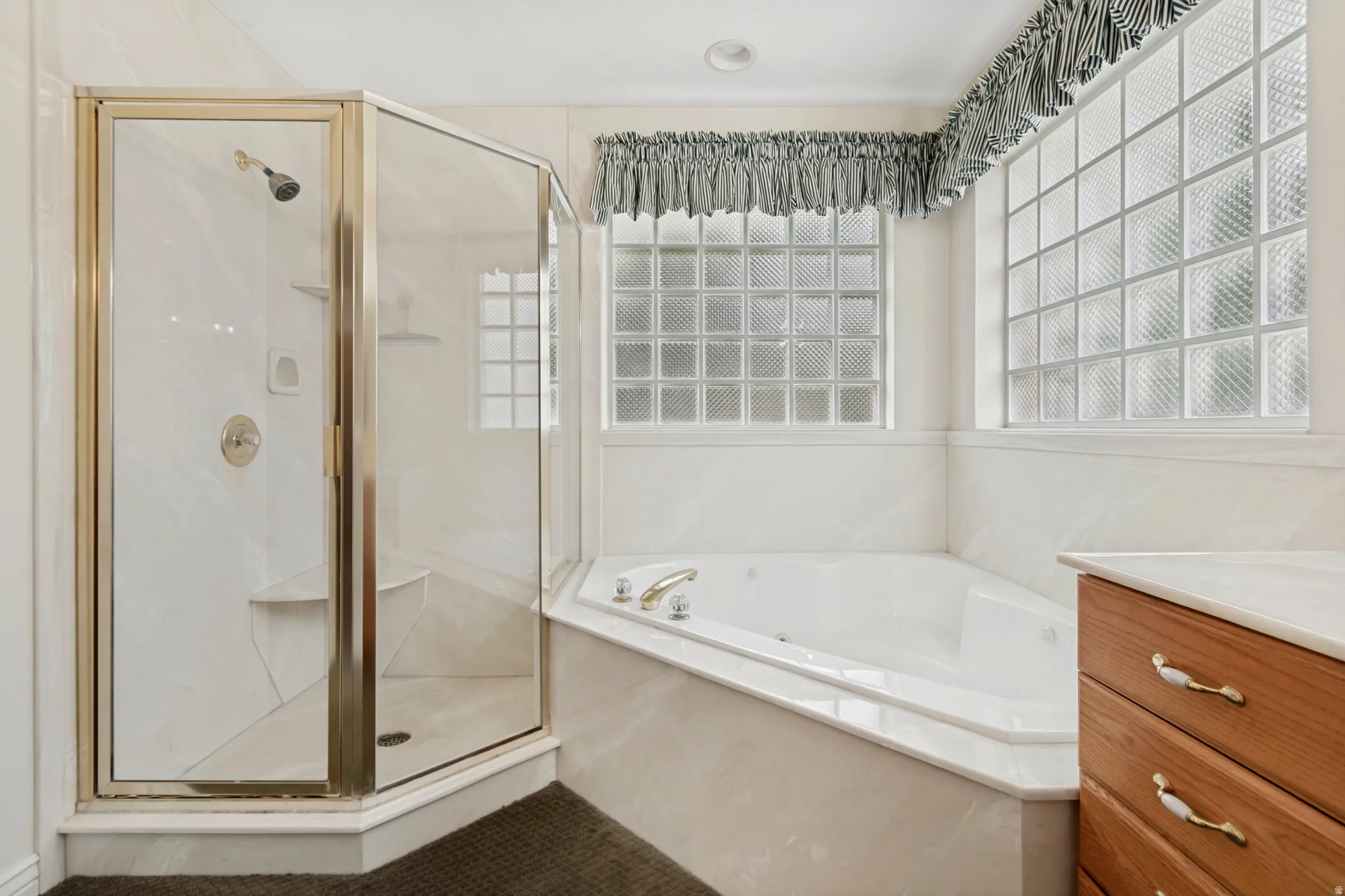 Corner shower enclosure with clear glass panels, built-in shower bench, and a corner soaking tub with deck-mounted fixtures