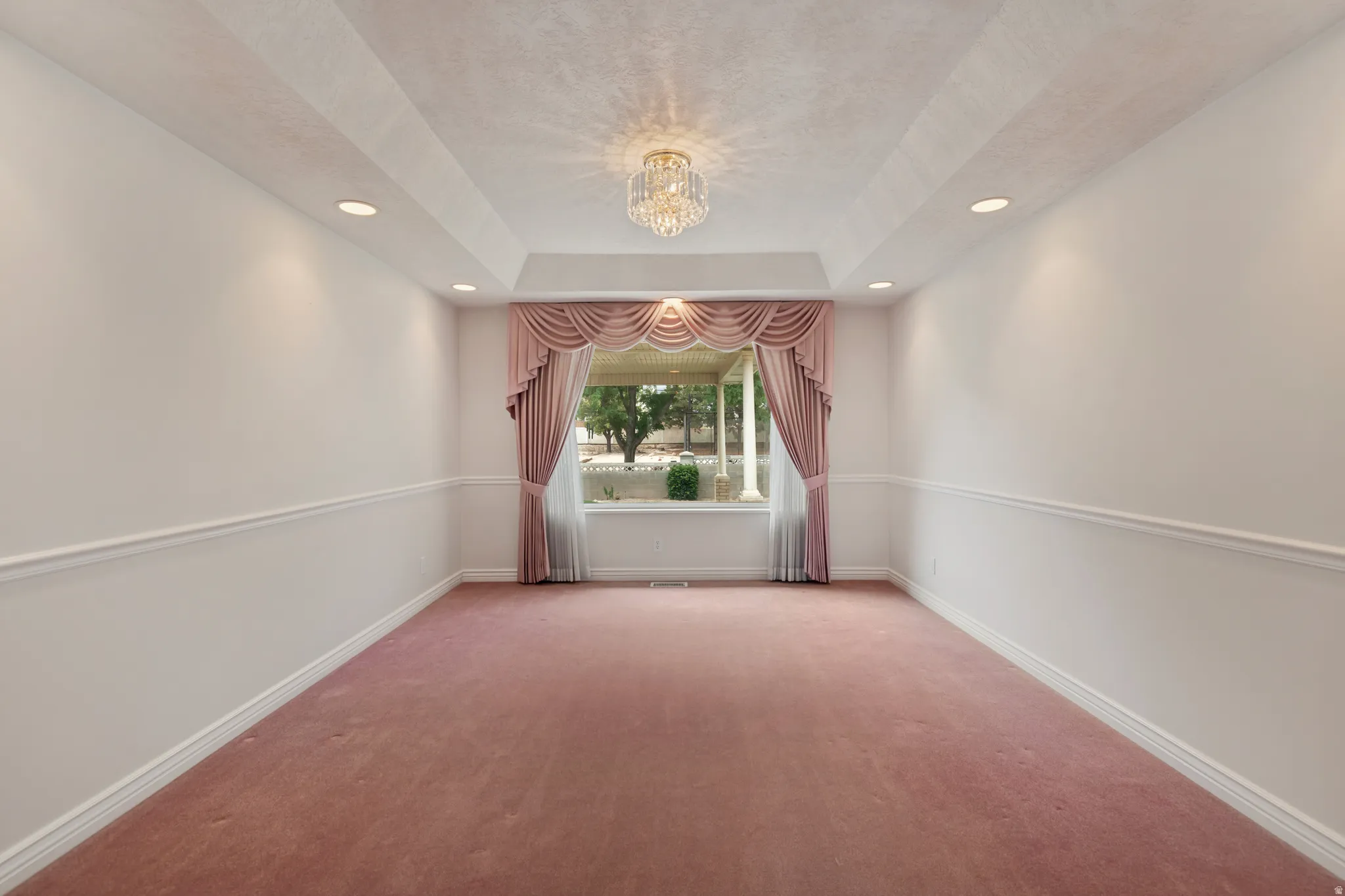 Tray ceiling with recessed lighting and a central chandelier