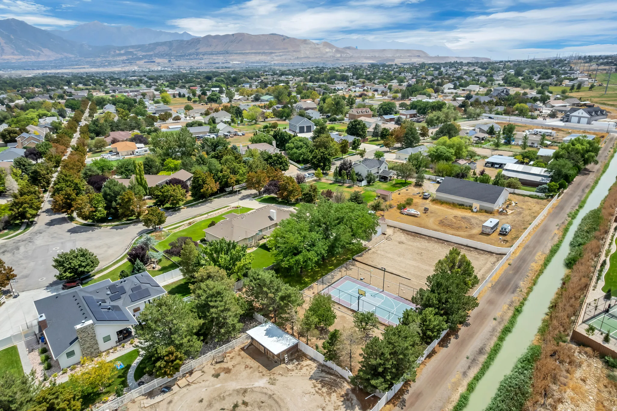 Expansive lot featuring a sports court, covered outdoor structure, and white fencing