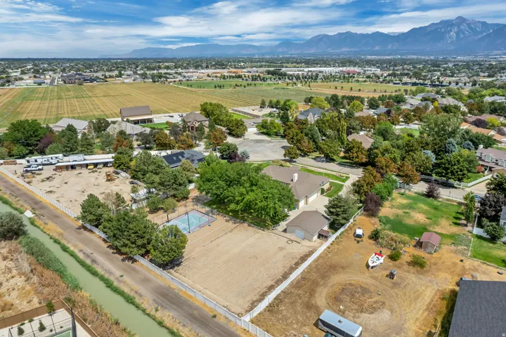 Expansive property featuring a paved sports court, multiple accessory structures, and a sizable undeveloped area