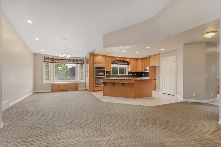 Open-concept living space with a kitchen featuring wood cabinetry, dark countertops, and stainless steel appliances