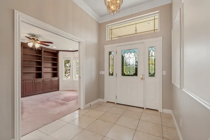 Entryway featuring tile flooring, a decorative glass front door with sidelights, and a transom window
