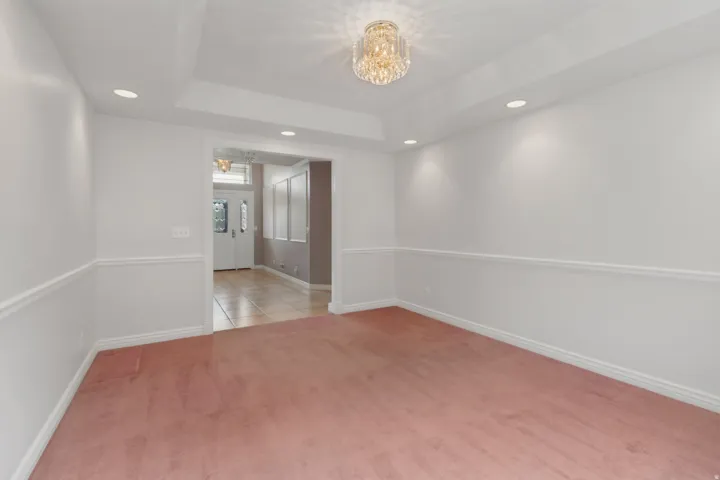 Recessed lighting, tray ceiling, crystal chandelier, chair rail molding, and an open doorway