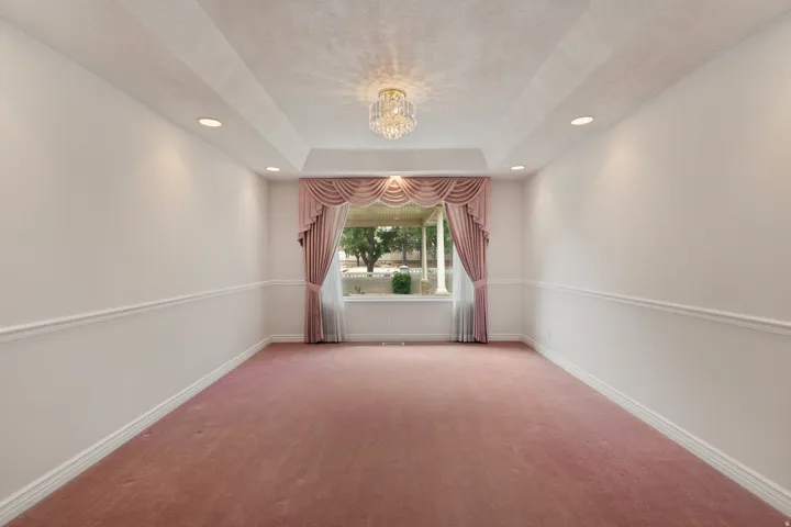 Tray ceiling with recessed lighting and a central chandelier