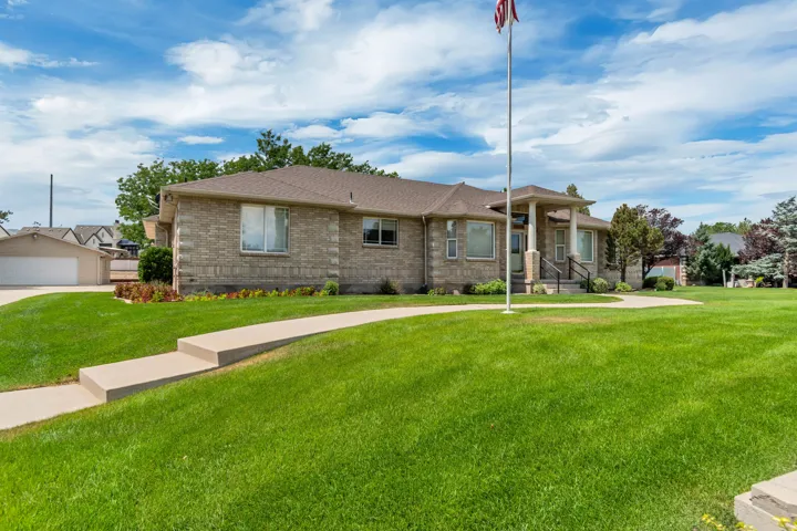 Brick exterior, covered front entry, concrete pathway, attached garage, and surrounding green lawn
