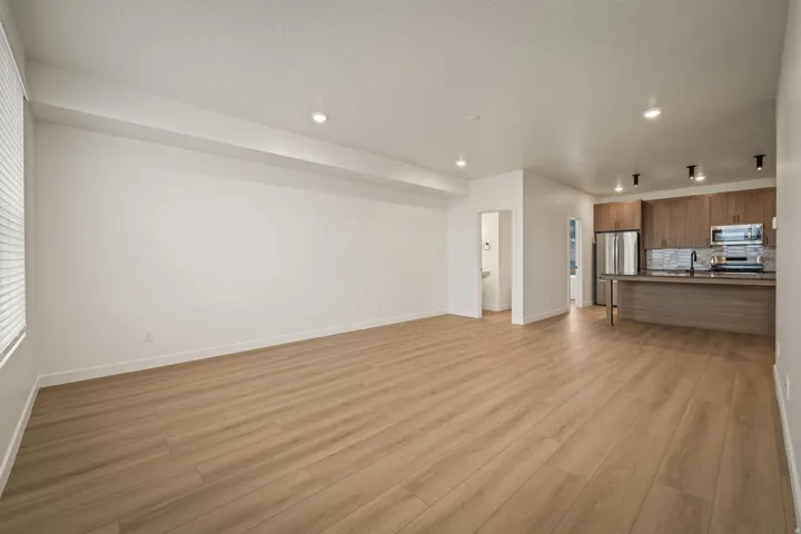 Recessed lighting, wood-finish flooring, white walls, wood-finish cabinetry, and stainless steel appliances