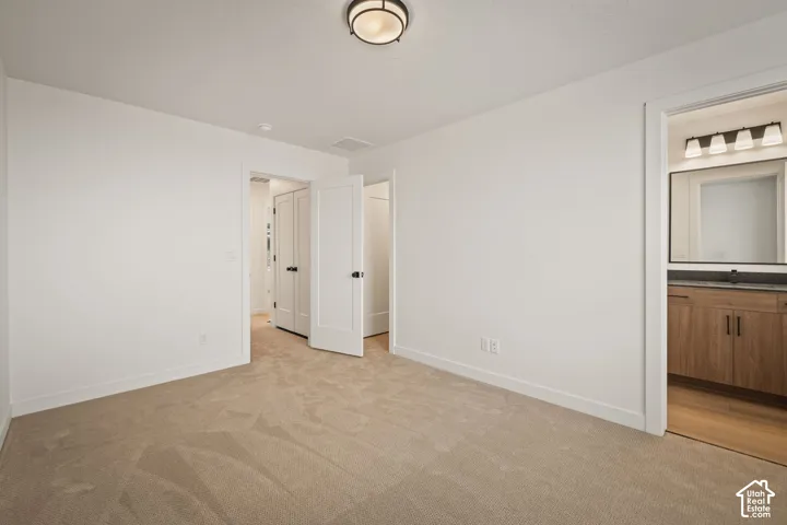 Neutral tone carpeting with white trim, wood-finish vanity with dark countertop, and modern light fixture